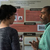 Eine Teilnehmerin steht mit Juan R. Valdez vor einem Plakat, Valdez erklärt