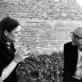 Black and white photograph of Gertraud Klemm und Claude Haas. They are engaged in conversation, Gertraud Klemm gestures with both hands.