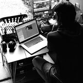 Auf dem Bild ist eine Person mit Kopfhörern von hinten zu sehen. Sie sitzt vor zwei Computern, auf denen die Videoaufnahmen aus dem Garten zu sehen sind.