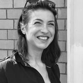 Black and white portrait of Kat Kaufmann, she smiles and looks up.