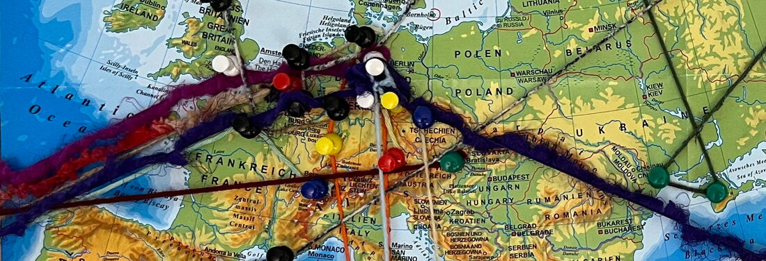 Kartenausschnitt von West-, Mittel- und Osteuropa (von Spanien/Großbritannien bis Ukraine), auf dem bunte Stecknadeln durch verschiedenfarbige Wollfäden verbunden sind.