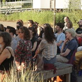 About 25 people sit in the audience on the open-air stage of Floating Berlin and listen to the reading.