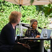 Ulrike Vedder and Yoko Tawada sit on a stage and talk to each other. In front of Tawada is a silver notebook.