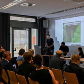 Nils Güttler stands at the lectern and speaks to the audience.