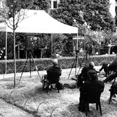 Iris Hanika und Ulrike Vedder sitzen auf einer kleinen Bühne und unterhalten sich. Davor sitzen Menschen auf Gartenstühlen und hören zu.