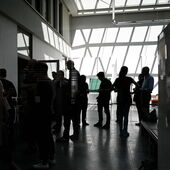 In the atrium of the Department for Cultural Study and History at HU Berlin, the dark outlines of several people can be seen against the light. The upper windows cast harsh shadows on the wall.