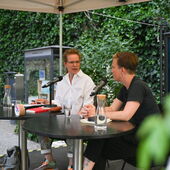 Katrin Trüstedt and Magdalena Schrefel sit on a stage and talk animatedly.