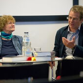 Monika Walter und Daniel Weidner sitzen auf Stühlen, Daniel Weidner gestikuliert mit seiner linken Hand.