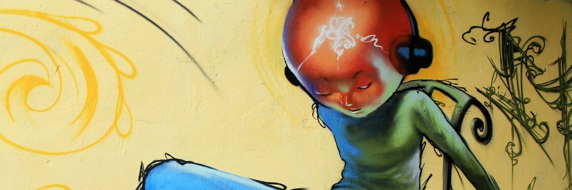 Graffiti of a character with a large orange and red head in a green long-sleeved shirt with headphones on their ears against a yellow background.