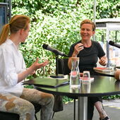 Katrin Trüstedt and Magdalena Schrefel sit on a stage and talk animatedly.
