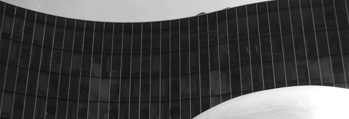 Schwarzweißer Ausschnitt einer geschwungenen verglasten Fassade.