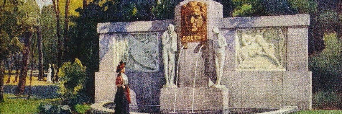 Malerei. Eine elegant gekleidete Frau betrachtet in einem Park einen weißen, imposanten Brunnen. Über zwei Öffnungen, aus denen Wasser in den Brunnen fließt, hängt ein bronzenes Porträt von Goethe mit seinem Namen als Unterschrift.