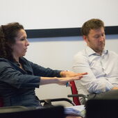 Nora Laafi und Markus Meßling sitzen auf Stühlen in einem Innenraum.