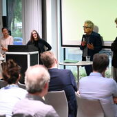Vier Personen stehen vor der Leinwand und diskutieren.