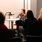 Durch die Publikumsreihen hindurch ist Olga Grjasnowa zu sehen. Sie ist auf ihrem Stuhl leicht zurückgelehnt und spricht nach rechts gewandt in ein Mikrofon.