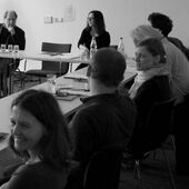 Black and white photography of conferees at conference table.