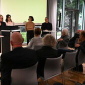 Vier Personen stehen vor der Leinwand und diskutieren.