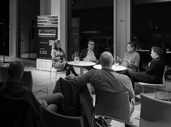 Black-and-white image: Panel discussion with four guests and audience