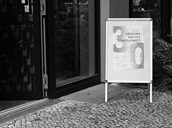 Aufsteller mit dem Veranstaltungsplakat vor der geöffneten Tür zum Konferenzraum.