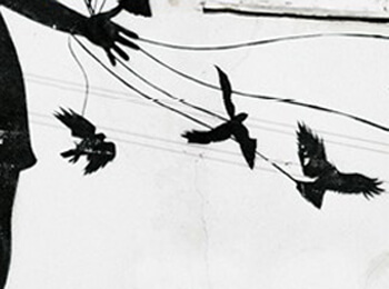 Silhouette of a hand with ribbons tied to birds on a wall.